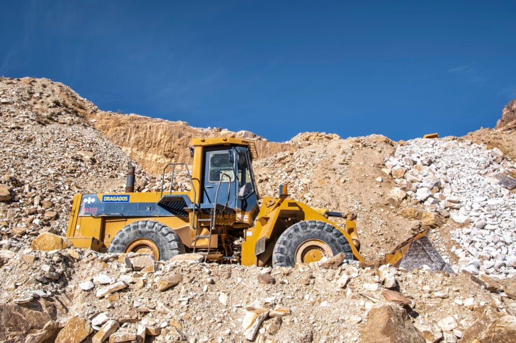 Industrial bulldozer operating in a sunny quarry with rocky terrain.